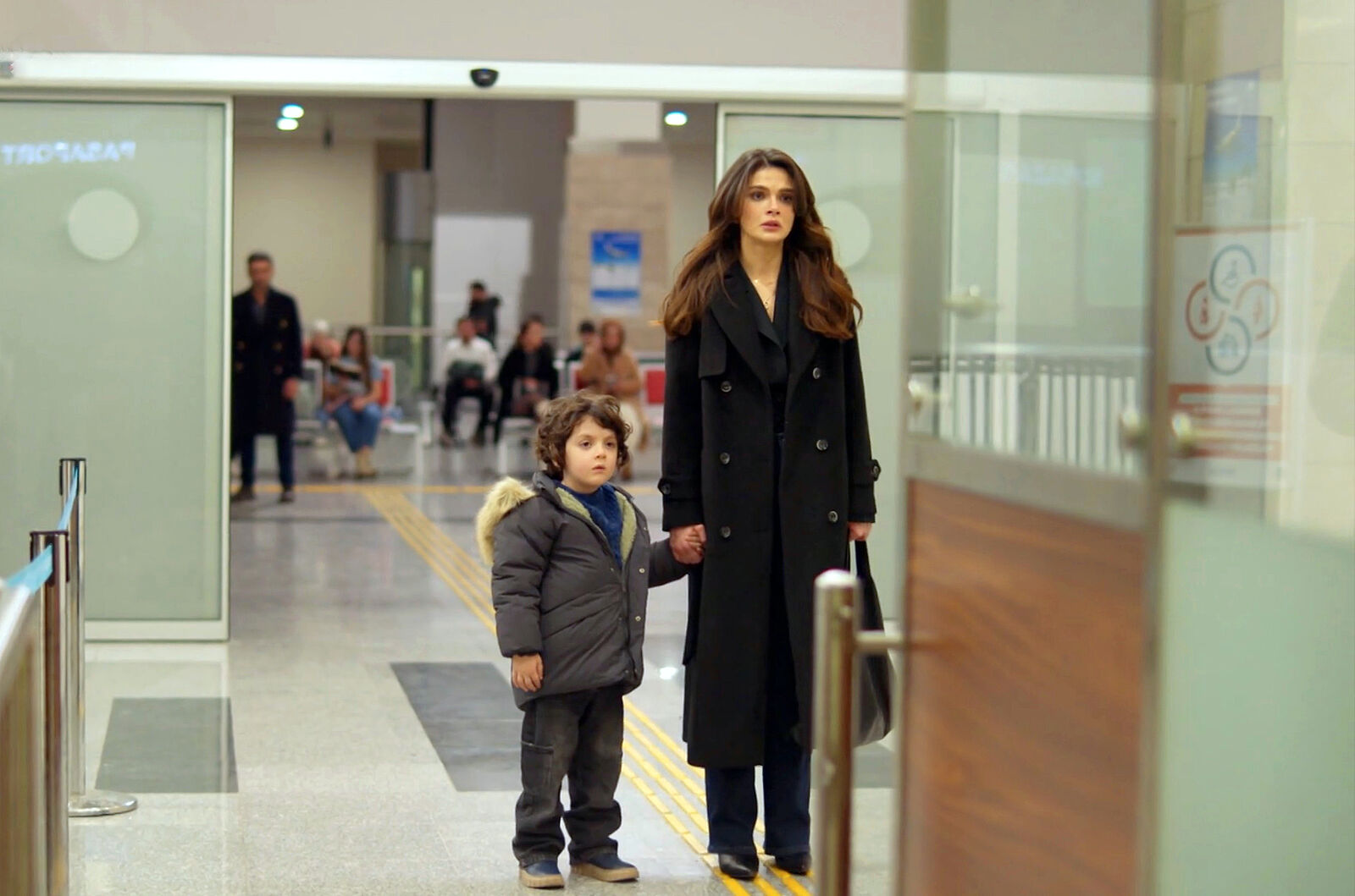 Cihan observa a Alya cuando está a punto de marcharse con Deniz para siempre en En tierra lejana